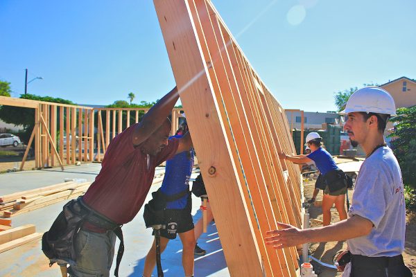 adult and young adults building a frame for recreation center